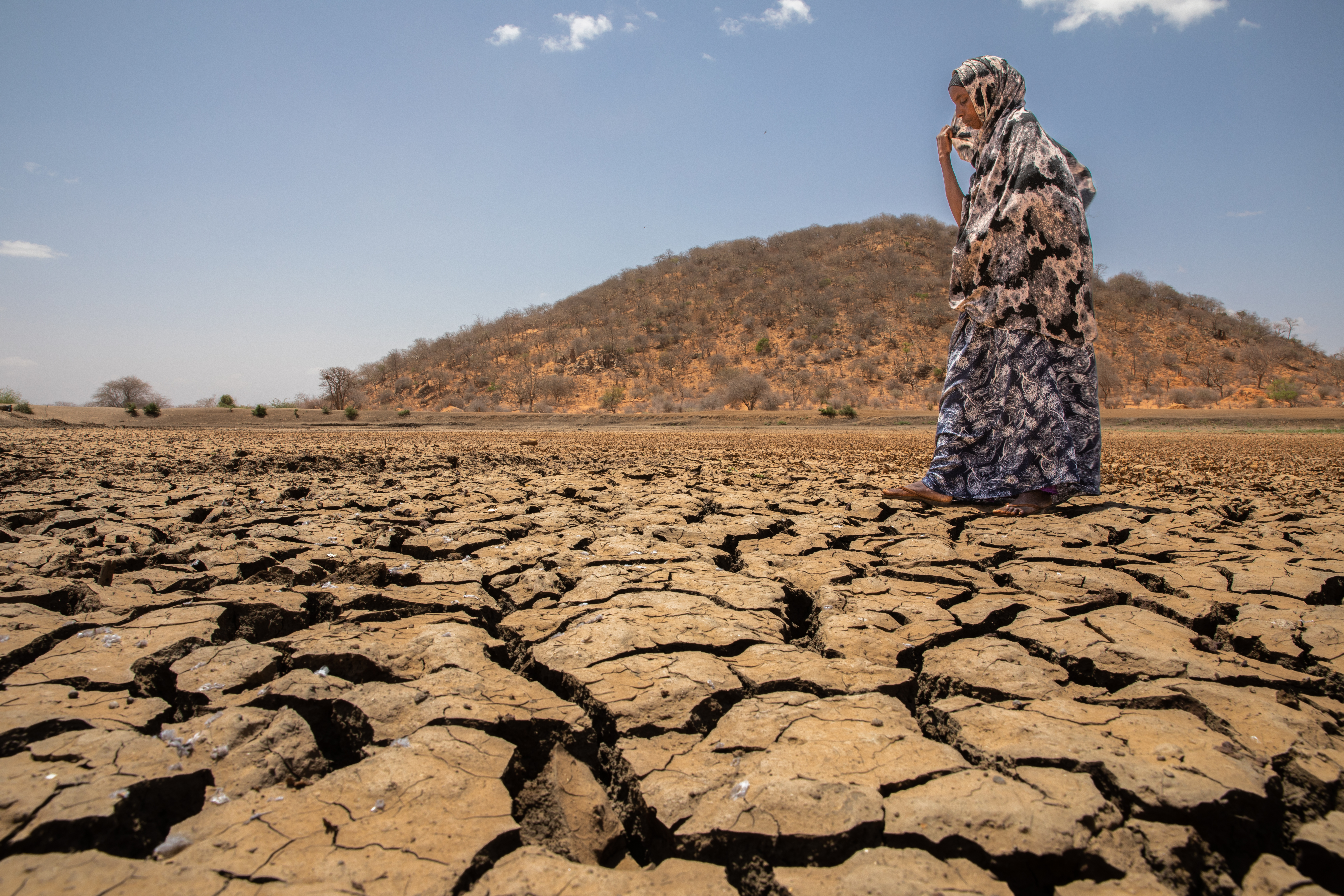 A person walking across dried earth.