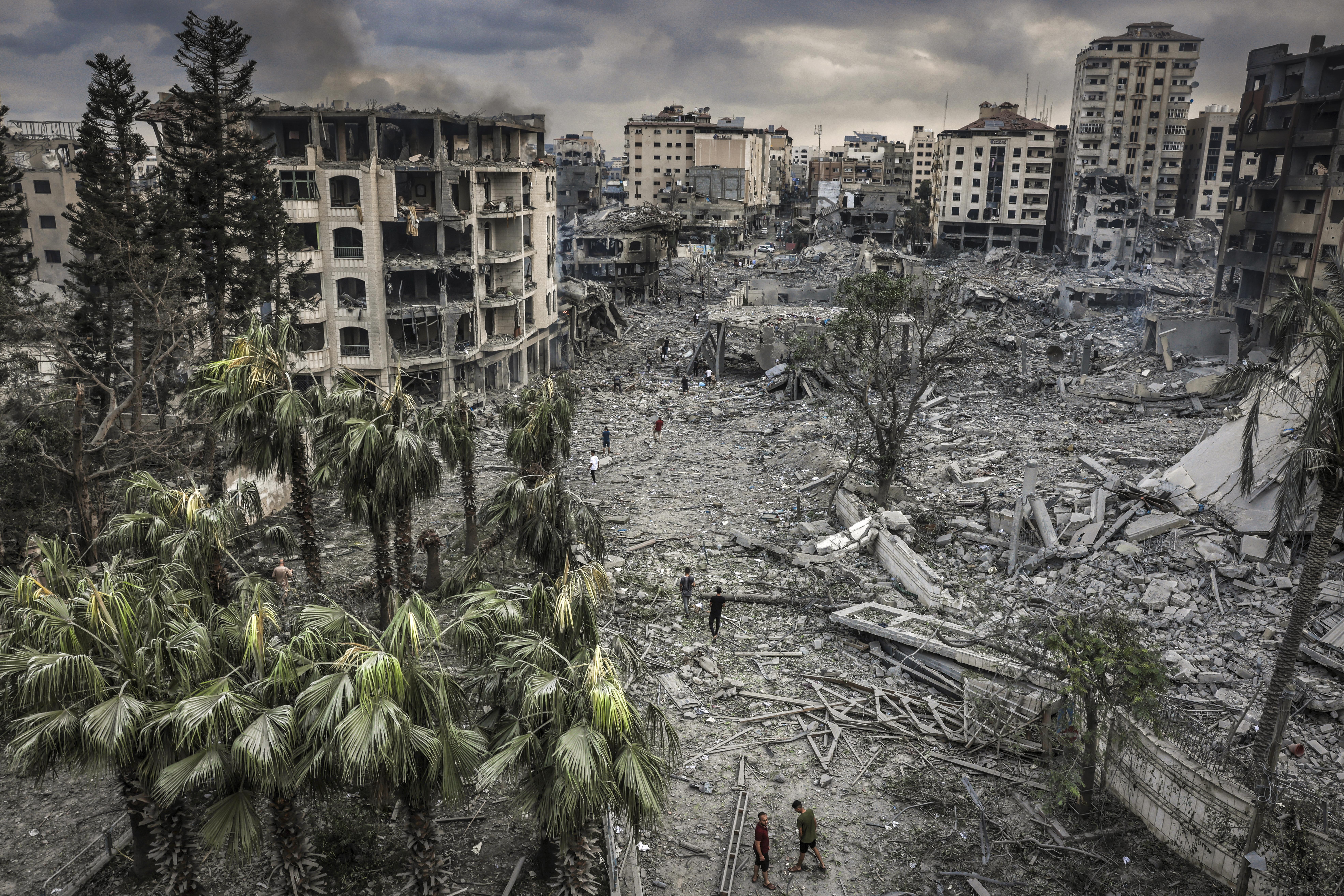 Residents walk through the rubble of the al-remal neighborhood in gaza city after it was destroyed by air raids. © eyad baba for mercy corps