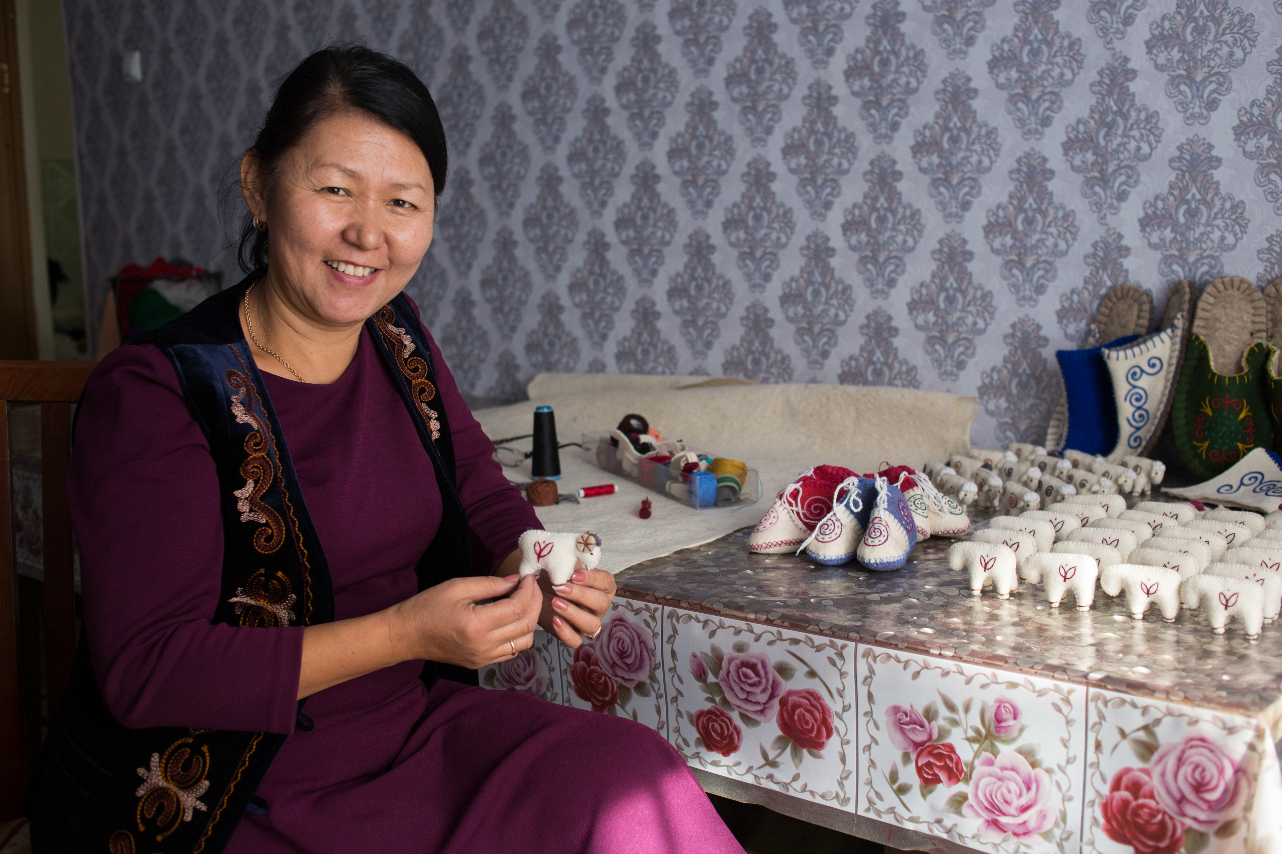 woman looking at the camera sewing a felt ram