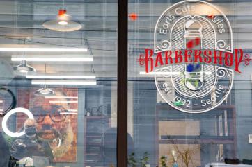 A barber cuts the hair of a customer inside a barbershop.