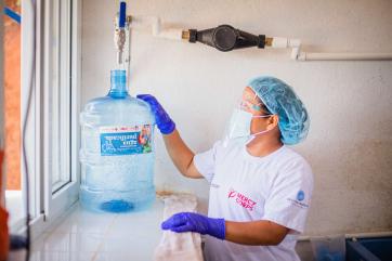 A worker with an empty water jug in a water purification center.