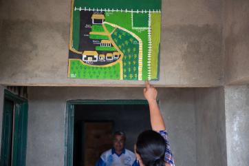 A farmer and landowner points to a map in their home.