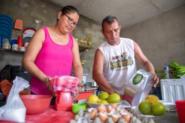 Colombian woman and man prepare commercial food together.