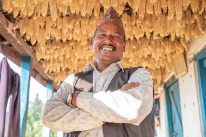 A person standing beneath drying corn outside their home. 