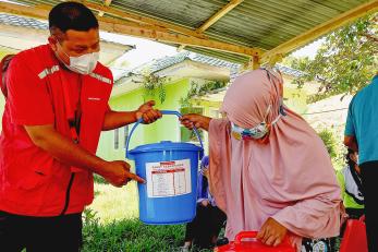 A person hands someone a hygiene kit.