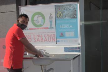 A person using a recycled bottle hand washing station.