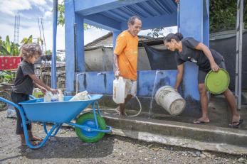 A family retrieves clean water from a water point built by mercy corps in timor-leste