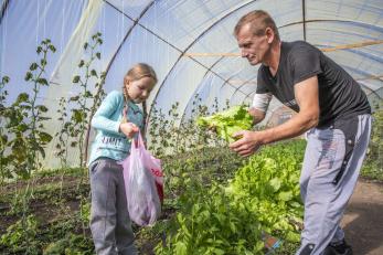 A girl and a man tend an indoor garden