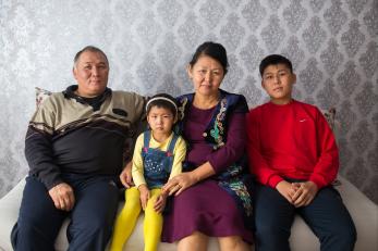 Father, daughter, mother and son seated together looking at the camera