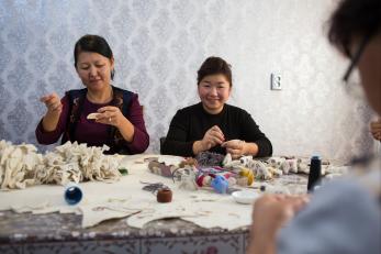 Women at a table sewing felted rams