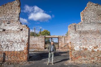 A person standing among crumbling building walls.