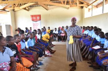 A person speaking to a room full of young people.