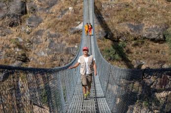 A person crossing a suspension bridge.