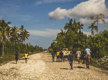 People walking along an unpaved road in haiti.