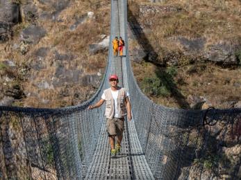 A person crossing a suspension bridge.