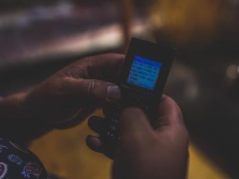 A pair of hands uses a mobile phone to send an sms text. 