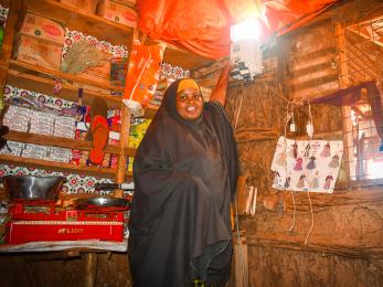 Somalian woman displaying the lighting in her store.