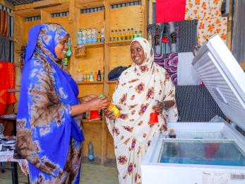 Two kenyan women interact in a commercial environment.