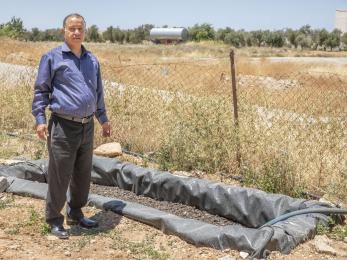 A person standing next to next to the greywater system at their home.